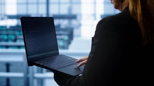 Midsection of woman using laptop at office