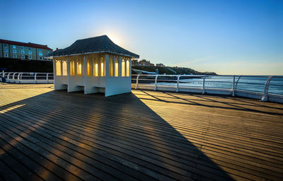 Pier over sea against clear blue sky