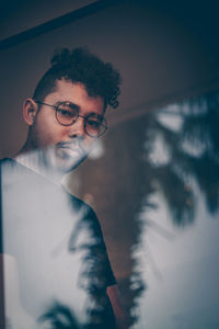 Portrait of serious young man seen through window