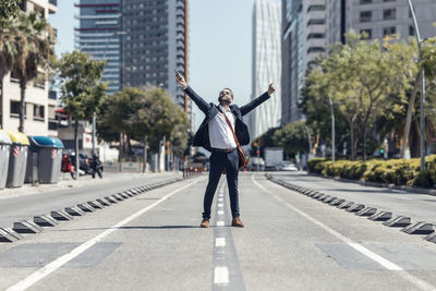 Happy businessman with arms outstretched on street in city
