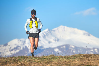 Rear view of man standing on mountain against sky