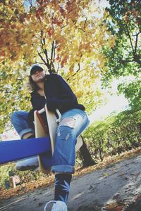 Full length of young man sitting on autumn leaves