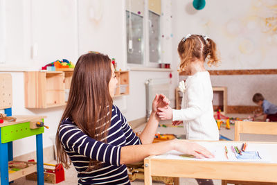 Mother and daughter standing on table