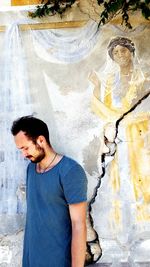 Thoughtful young man standing against mural wall