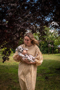 Portrait of young woman standing against trees