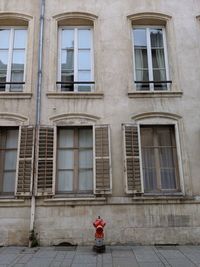 Fire hydrant against  old stone building facade in nancy, france.