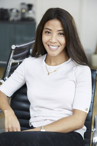 Portrait of smiling businesswoman sitting on chair at office