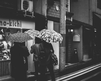 Rear view of people walking on street in rain