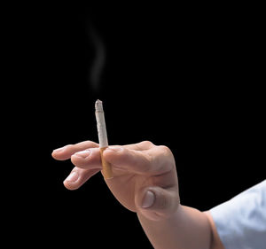 Hand holding cigarette against black background