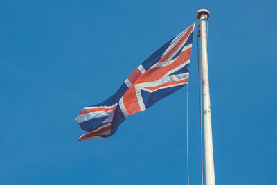 Low angle view of flag against blue sky