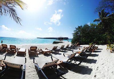 Panoramic view of chairs on beach against sky