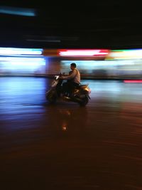 Man riding motor scooter on road at night