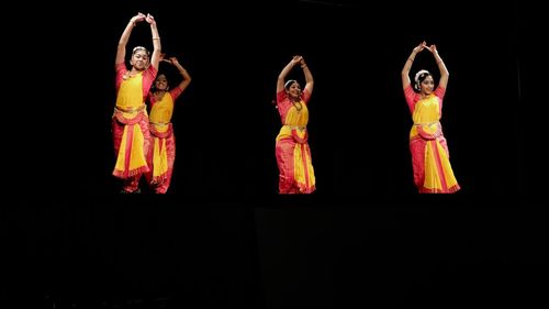 Low angle view of women standing against black background