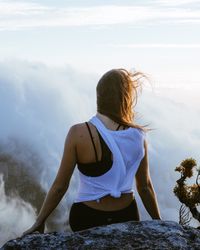 Rear view of woman standing by sea against sky