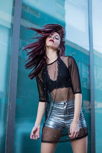 Portrait of beautiful woman standing against window