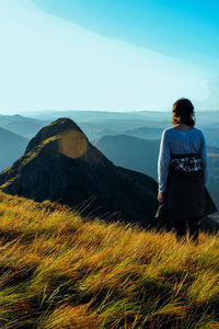 Rear view of man standing on landscape against sky