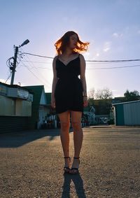 Full length of young woman standing against sky