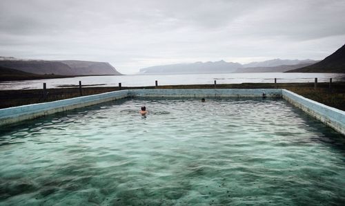 View of swimming pool by sea against mountains