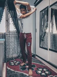 Full length of young man standing by window