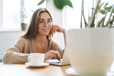 Portrait of young woman using mobile phone on table