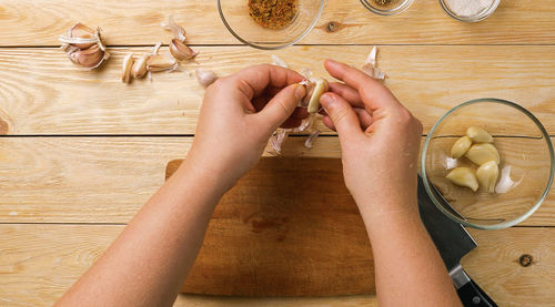 Peeling garlic from the husk in the home kitchen. a woman's hands peel garlic and put it in a bowl.