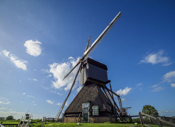 Low angle view of traditional windmill against blue sky