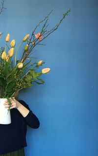 Woman holding flowers by blue background