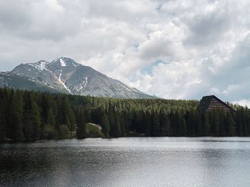 Scenic landscape of mountain lake with green forest and hotel in background. storm clouds.