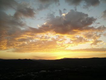 Silhouette landscape against dramatic sky during sunset