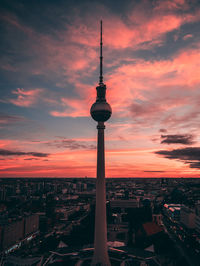 Fernsehturm in city against romantic sky during sunset