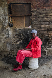 Portrait of man sitting against brick wall