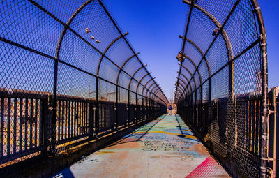 Chainlink fence bridge against sky