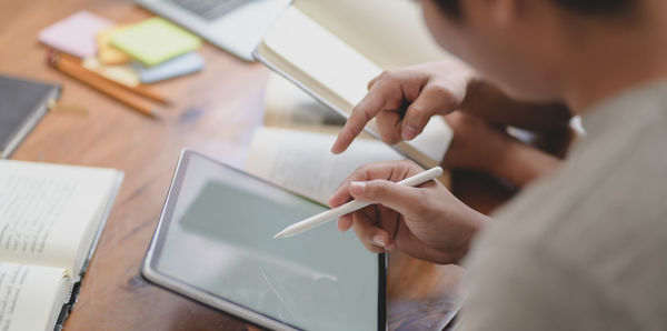 Midsection of man using mobile phone on table