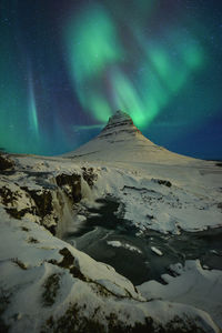 Scenic view of snowcapped mountains against sky at night