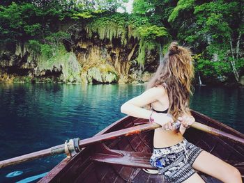 Rear view of woman standing by boat in lake