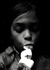 Close-up of girl eating marshmallow in dark