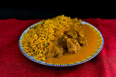 Close-up rice and curry served in plate on table against black background