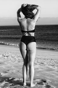 Full length rear view of bikini woman standing at beach