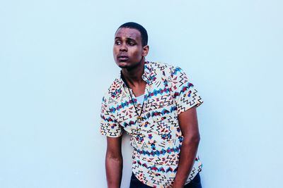 Low angle view of young man standing against colored background