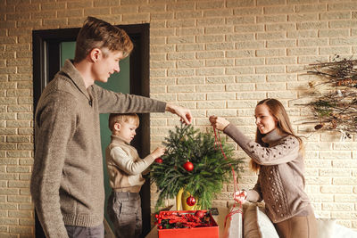 Family decorating the christmas tree against wall