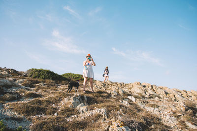 Women with dog on rocks against blue sky