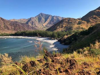 Scenic view of lake and mountains against clear blue sky