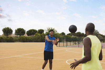 Son throwing ball to father playing at basketball court