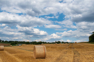 Hay bales on field against sky