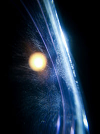 Low angle view of illuminated lighting equipment against black background