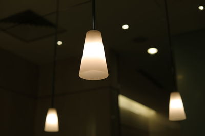 Low angle view of illuminated light bulb hanging from ceiling