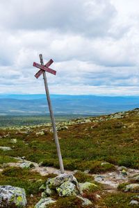 Cross on land against sky