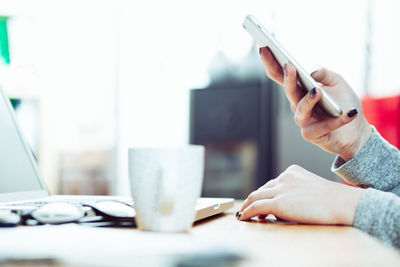 Midsection of person using mobile phone on table