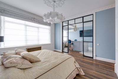 Large bright room with blue walls and a huge white chandelier and glass wall