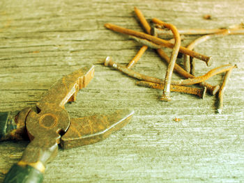 Close-up of old rusty pliers and nails on wooden table